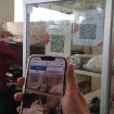 Pembeli sedang membayar belanjaannya dengan menggunakan QRIS (QR Code Indonesian Standard) untuk transaksi jual beli. Inggrid Aulia K/Kalamoeda