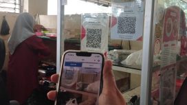 Pembeli sedang membayar belanjaannya dengan menggunakan QRIS (QR Code Indonesian Standard) untuk transaksi jual beli. Inggrid Aulia K/Kalamoeda
